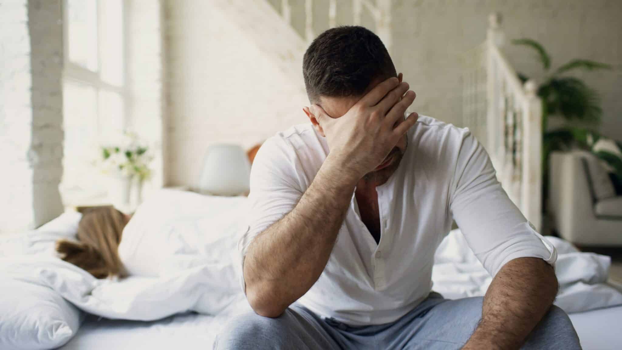 Man Seated on Bed Looking as if he's under Emotional Tension and Stress.